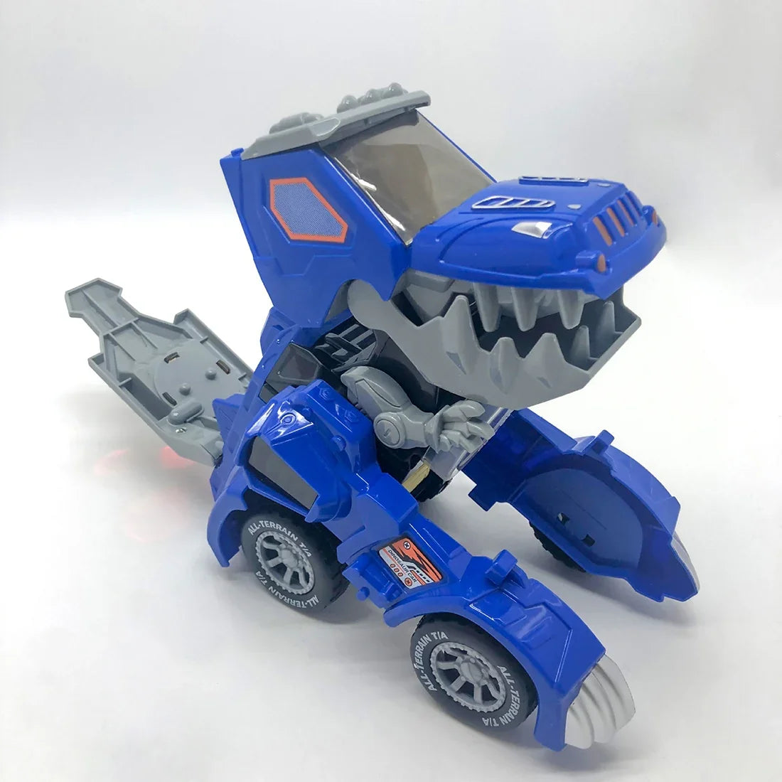 Blue dinosaur transformer toy with wheels, gray jaw, and all-terrain tires on white background.